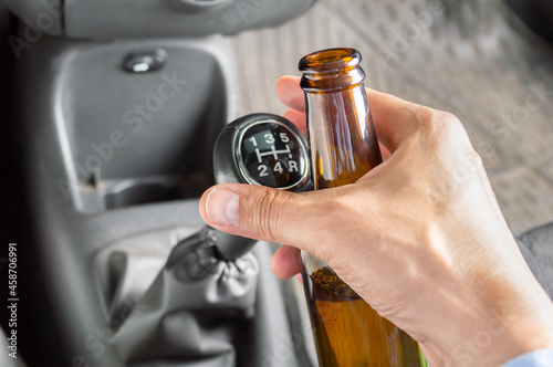 Close-up of hand driving car and drinking alcohol dangerously