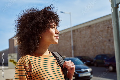 Cute young woman walking with a backpack outdoors