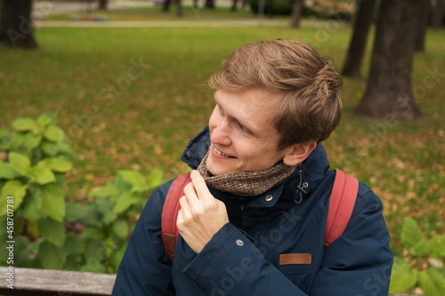 Portrait of man in autumn park. Warm coat. Knitted scarf.