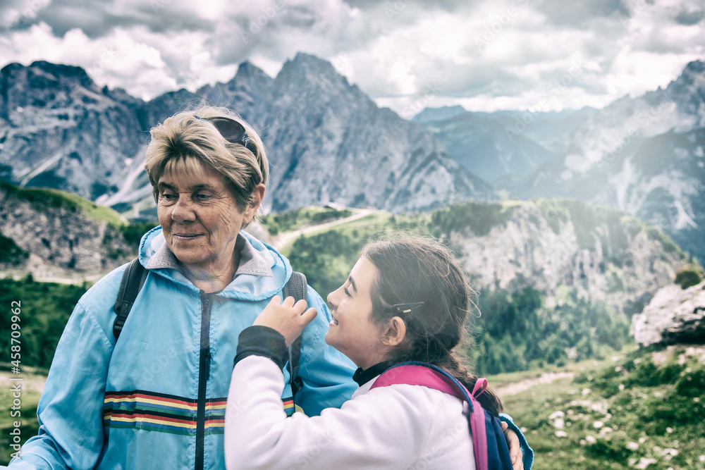 Elderly woman along a mountain trail with her grand daughter.