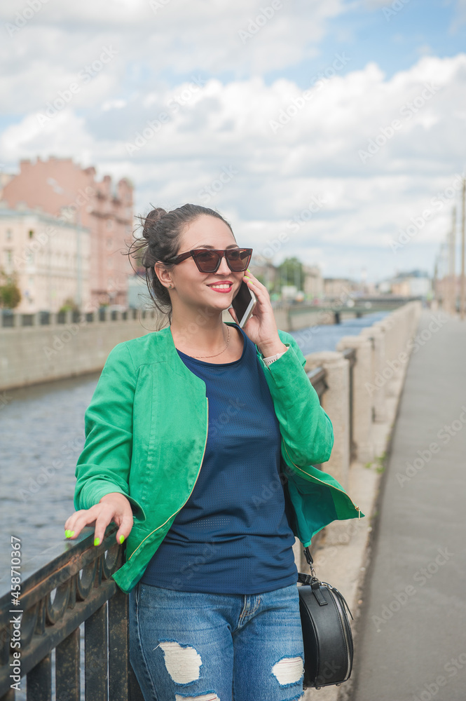Beautiful stylish woman posing in the city and talking on mobile phone