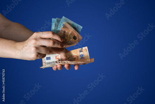 Hands counting many euro bills on blue background