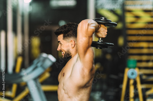 Profile of a strong man exercising with weights in a gym