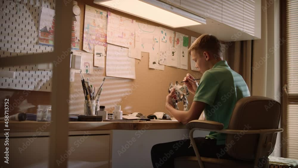 Little boy focused on work. Painting robot skeleton in his room Little boy focused on work. Painting robot skeleton in his room