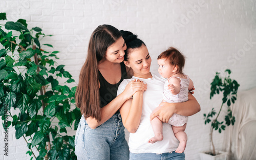 A young happy female couple and their child are enjoying together at home. lesbian couple