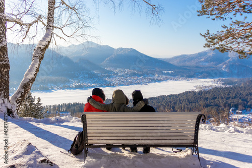three friends relax on a bench in winter
