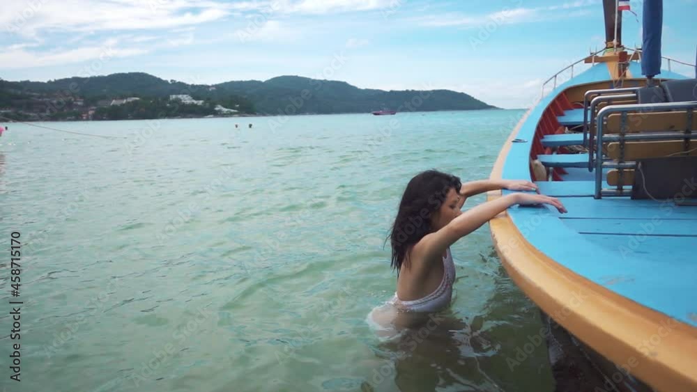 Woman jump into long tail boat. Tourism and recreation in Thailand. Charming cute Asian woman travel around the islands. The girl enjoy life and has fun. Paradise beaches and white sand