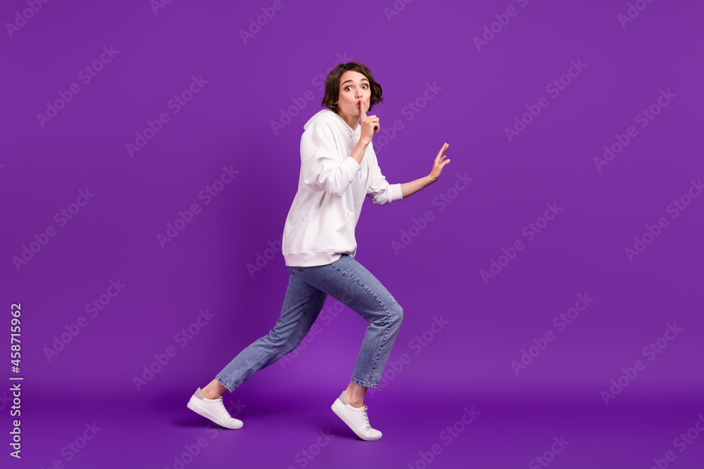 Full size photo of young serious girl show shut-up gesture running away hiding isolated on purple color background