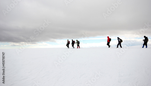 Group of mountaineers walking trough the mountains covered with snow... © Kybele