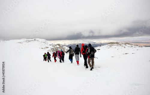 Group of mountaineers walking trough the mountains covered with snow...