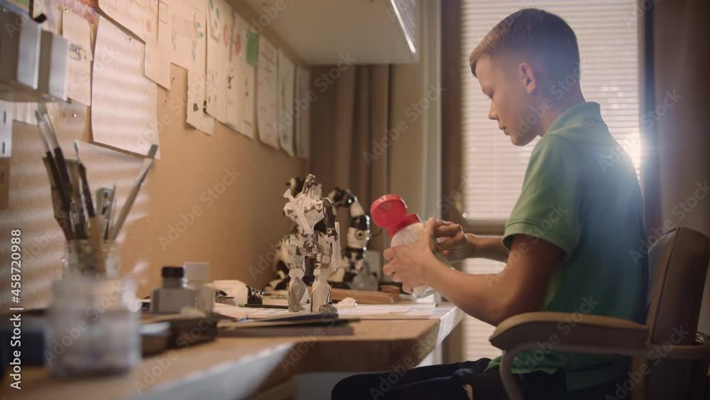 Little boy focused on work. Painting robot skeleton in his room Little boy focused on work. Painting robot skeleton in his room