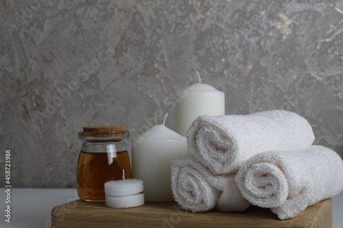 Spa relax massage home care for soy body. White candles towels oil in a jar bottle scrub on a white gray background with space for text. Beauty parlour