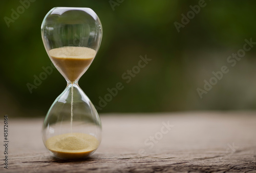 Sand clock , Hourglass as time passing on green nature background , Life time concept