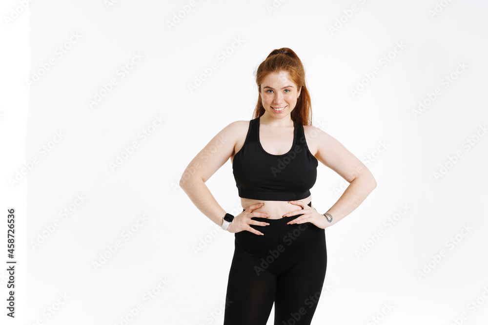Young ginger woman smiling while holding her hands on waist Young ginger woman smiling while holding her hands on waist