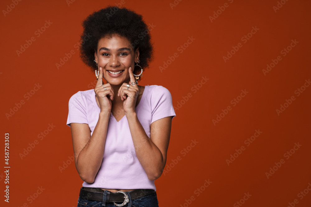 Young black woman smiling and pointing fingers at her cheeks Young black woman smiling and pointing fingers at her cheeks