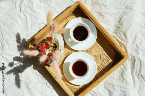 Breakfast in bed, try with two cups coffee and flower in sunlight at home, chambermaid bringing tray with breakfast in hotel room, good service