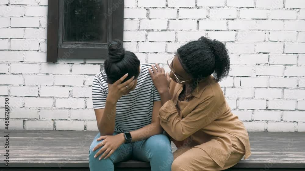 Depressed unhappy young female sitting while her african woman friend trying to support her. Friend's help during depression and anxiety Depressed unhappy young female sitting while her african woman friend trying to support her. Friend's help during depression and anxiety