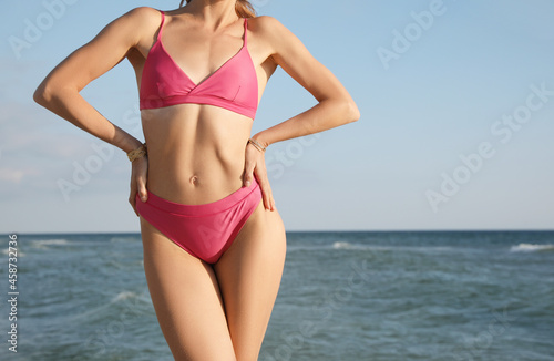 Woman with beautiful body in bikini near sea, closeup