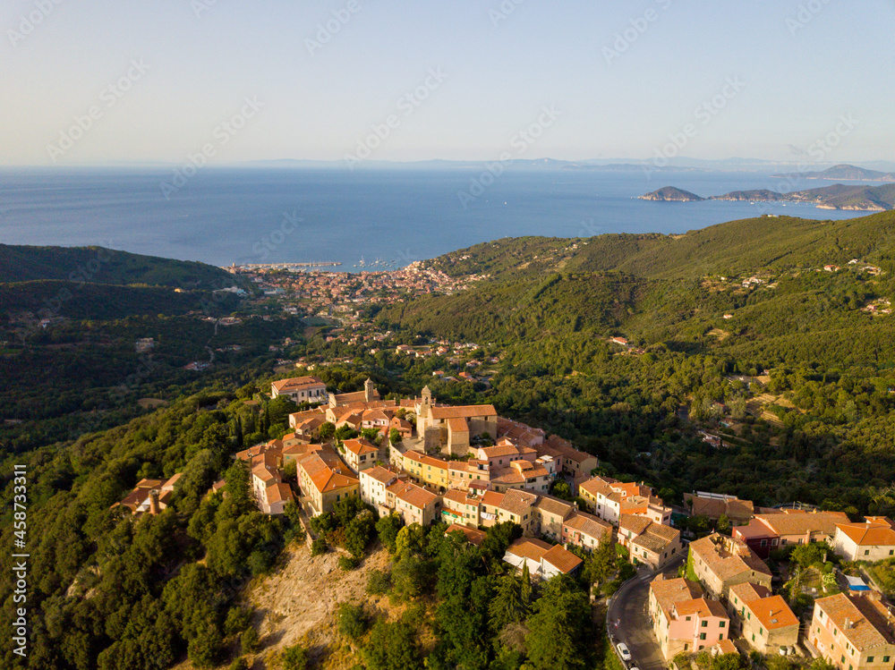 Aerial Drone Panorama of mountain old town Marciana on the islands of Elba Italy with green trees and the mediterranean sea ocean in the background