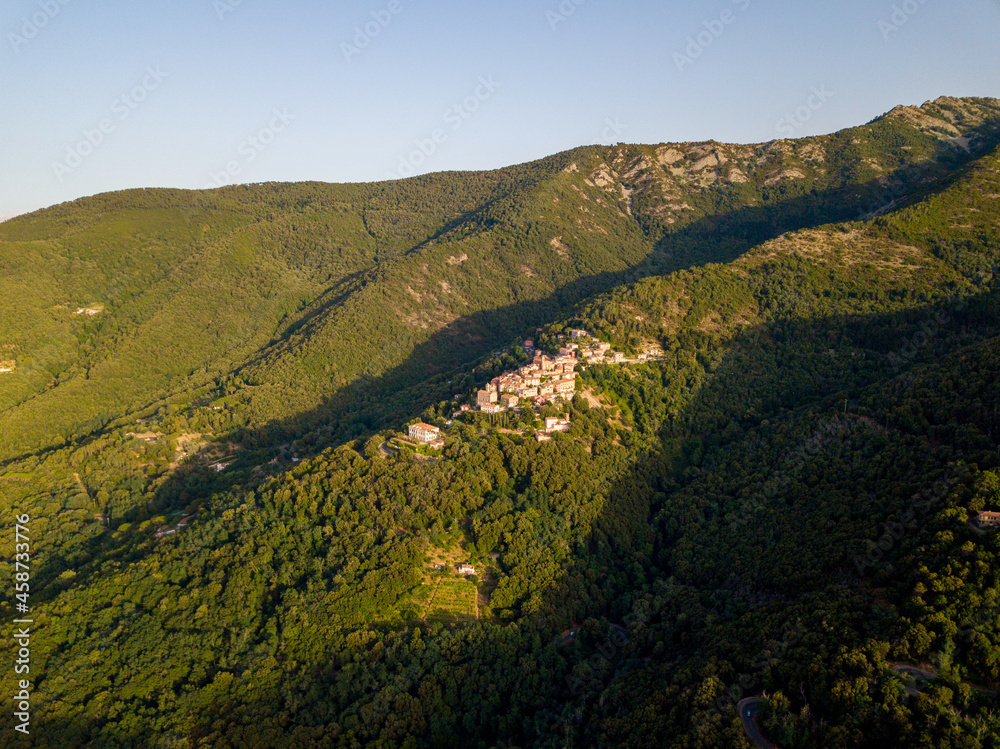 Fototapeta premium Aerial Drone Panorama of mountain old town Marciana on the islands of Elba Italy with green trees and the mediterranean sea ocean in the background