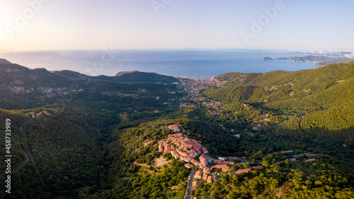 Aerial Drone Panorama of mountain old town Marciana on the islands of Elba Italy with green trees and the mediterranean sea ocean in the background