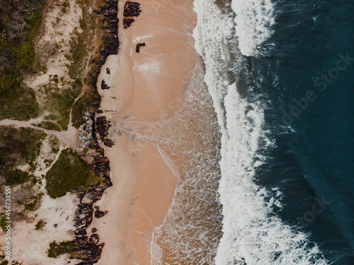 Drone shot of waves crashing on a beach from above