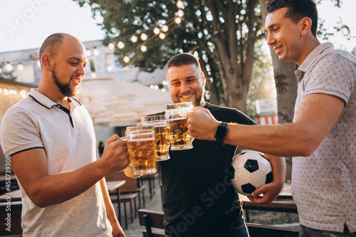 Friends drinking beer together at pub and watching football