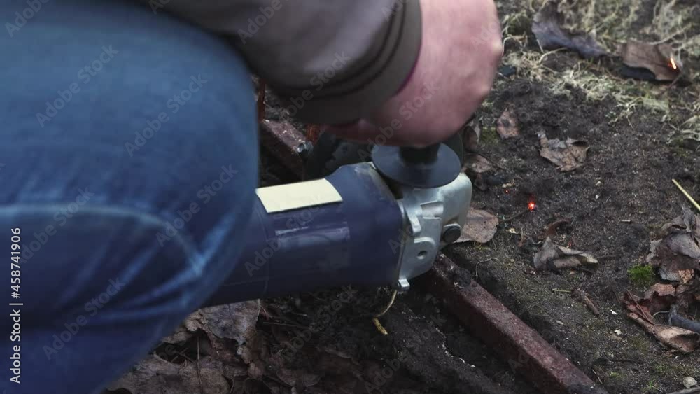 Male hands with an angle grinder are cutting the old, destroyed metal structure. Bright sparks fly from the spinning disc. The concept of working with metal with an electric cutting tool. UHD 4K. Male hands with an angle grinder are cutting the old, destroyed metal structure. Bright sparks fly from the spinning disc. The concept of working with metal with an electric cutting tool. UHD 4K.