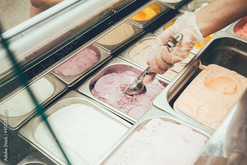 Ice cream seller picks up soft italian ice cream in a ball. Ice cream refrigerator
