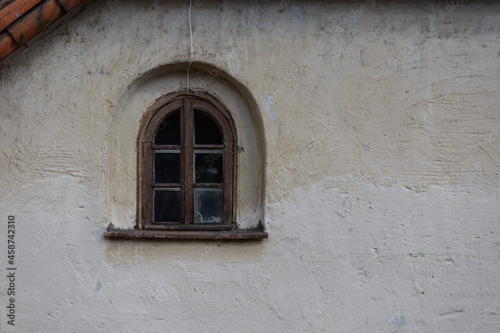 Fototapeta premium a small window of an old medieval house. a garland of diode lights hangs from the roof. the wall of the house is finished with gray plaster