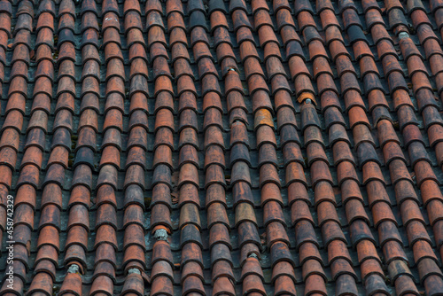 An old roof tiles pattern. Dark red weathered and aged tiles covering roof of old european house © Дмитрий Березнев