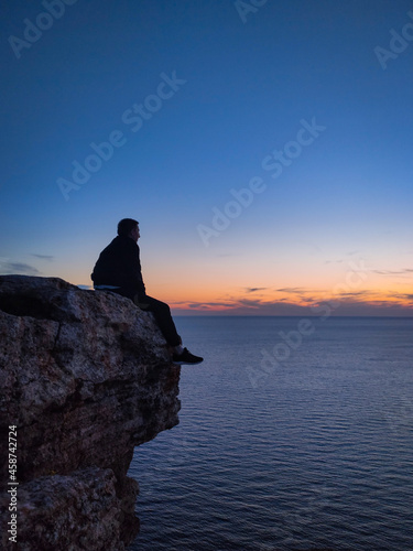 a man sits on a rock by the sea