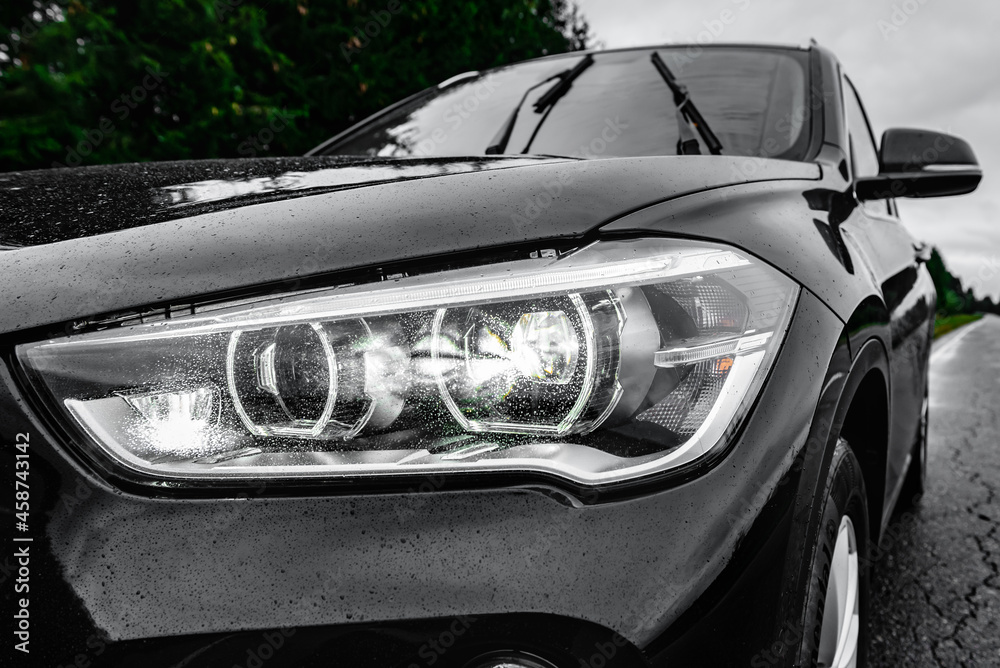 Headlight lamp of new car on road in rainy day.