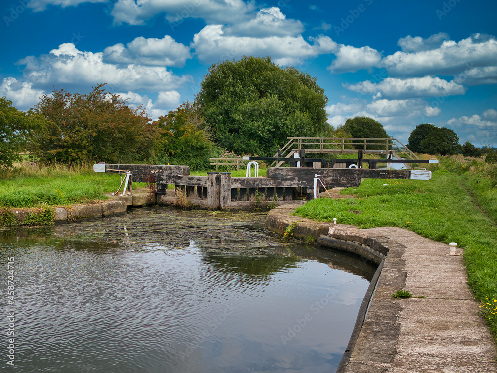 Fototapeta premium Moss Lock (4) and footbridge on the Rufford Branch of the Leeds Liverpool Canal in Lancashire, UK. Taken on a sunny day in summer.