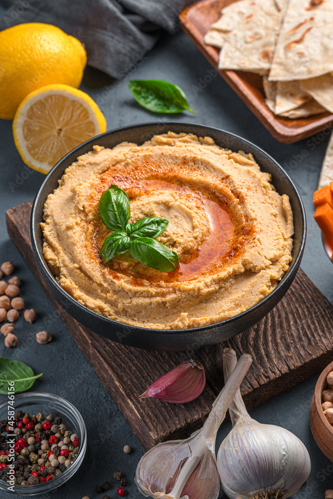Hummus with olive oil and paprika on the background of ingredients. Side view, vertical. Hummus with olive oil and paprika on the background of ingredients. Side view, vertical.