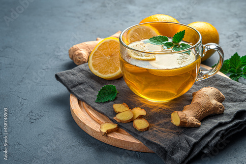 Healthy, warming tea with ginger and lemon on a dark background. A drink that strengthens the immune system. Side view, copy space