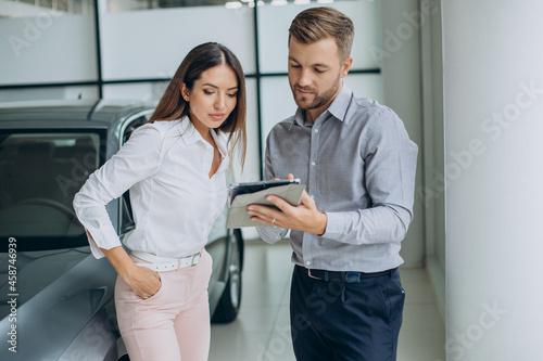 Young business woman buying a car in car showroom