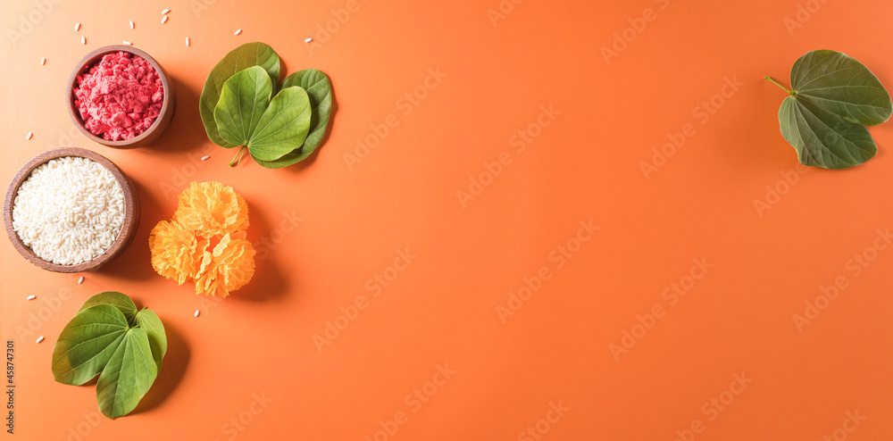 Happy Dussehra. Yellow flowers, green leaf and rice on orange background. Dussehra Indian Festival concept. - obrazy, fototapety, plakaty 