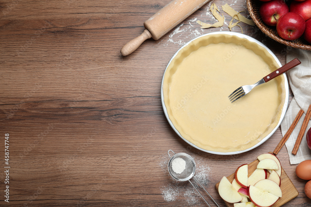 Flat lay composition with raw dough, fork and ingredients on wooden table, space for text. Baking apple pie Flat lay composition with raw dough, fork and ingredients on wooden table, space for text. Baking apple pie