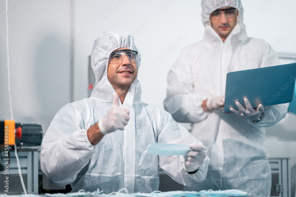 Scientists wearing uniform protection. Check the manufacturing process of face masks. In a laboratory at industry plants. The concept for security and protection coronavirus covid-19. Scientists wearing uniform protection. Check the manufacturing process of face masks. In a laboratory at industry plants. The concept for security and protection coronavirus covid-19.