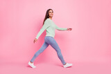 Full length profile photo of cheerful young brunette lady go wear pullover jeans sneakers isolated on pink background