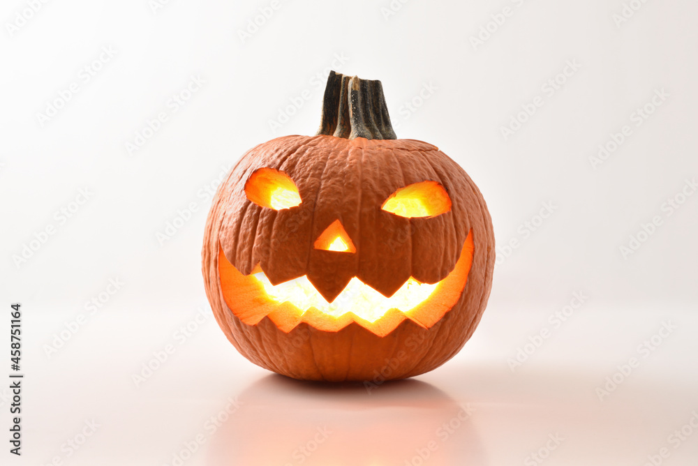 Carved and illuminated halloween pumpkin reflected on white table isolated Carved and illuminated halloween pumpkin reflected on white table isolated