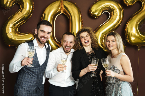 Beautiful well dressed party people celebrating 2022 New Year and drinking sparkling wine