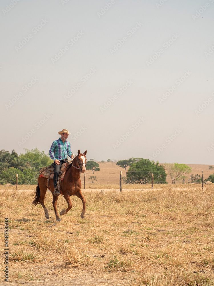 Cowboy is riding his horse on a cattle farm with very dry land Cowboy is riding his horse on a cattle farm with very dry land