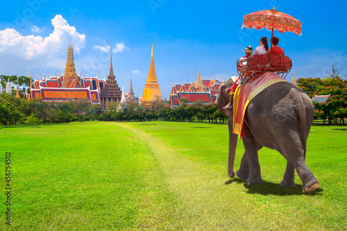 Tourists on an ride elephant dressing with thai kingdom tradition at the Buddhist temple of Wat Phra Kaeo at the Grand Palace in Bangkok,Thailand © thanapun