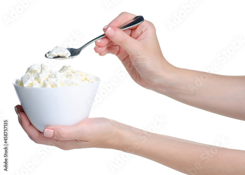 Hand holding cottage cheese in bowl with spoon on white background isolation