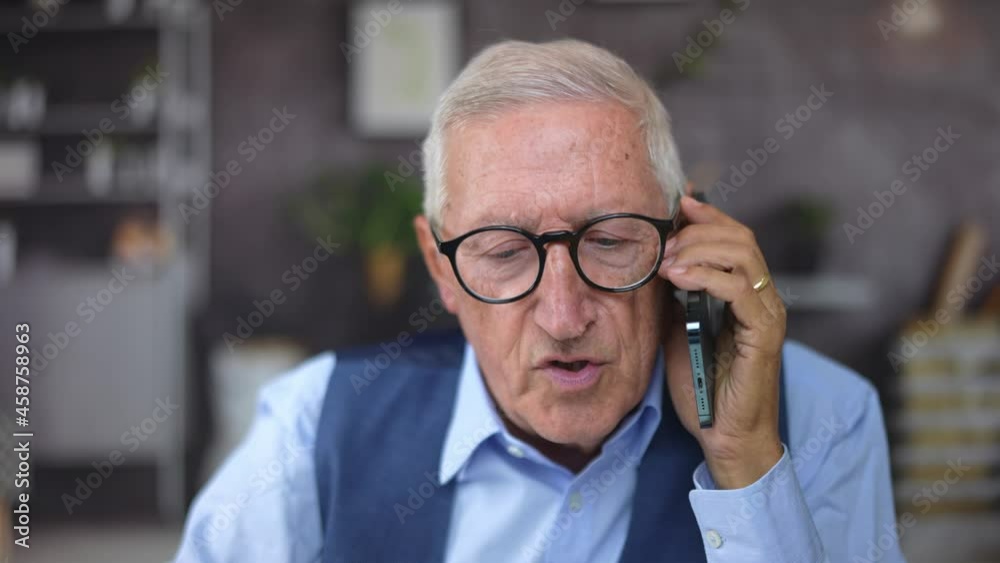 Portrait closeup of a disappointed mature businessman with black modern glasses talking on the phone at the office or at home. Portrait closeup of a disappointed mature businessman with black modern glasses talking on the phone at the office or at home.
