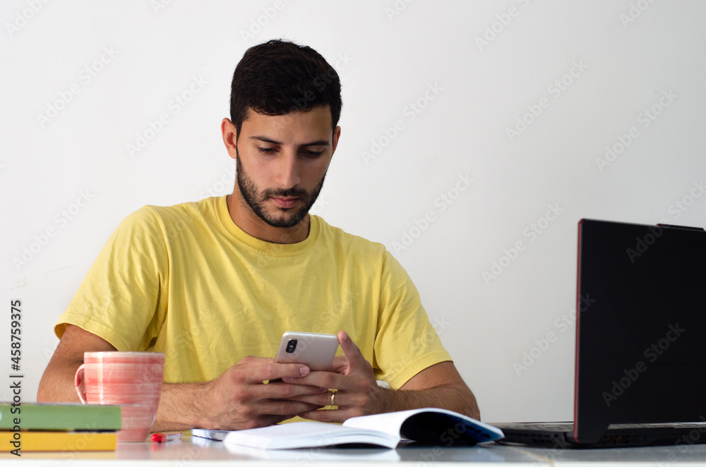 Young happy businessman smiling while reading his smartphone. concentrated student looking for information on his phone. concept of working at home Young happy businessman smiling while reading his smartphone. concentrated student looking for information on his phone. concept of working at home