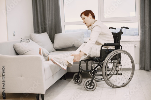 Senior woman trying to sit down in wheelchair from couch