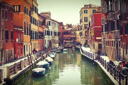 Channel in Venice with bridge boat gondola and old authentic italian houses. Cloudy day in old town. Italy.